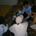 Through Mr. Aung of PEACE MYANMAR Electric Co., Anne Chiang of Goo Central briefs Burmese application contractors on the finer points of spraying on GOO on site in the exhibition hall.